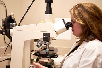 Lab technician looking through microscope